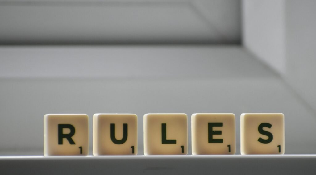 Identical small square shaped cubes with RULES title and numbers on white windowsill near window in house in daylight