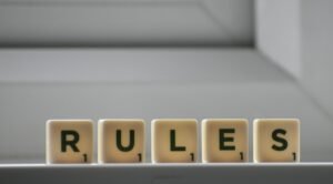 Identical small square shaped cubes with RULES title and numbers on white windowsill near window in house in daylight