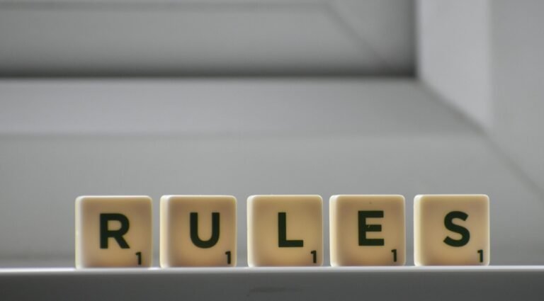 Identical small square shaped cubes with RULES title and numbers on white windowsill near window in house in daylight
